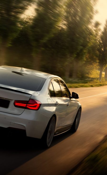 Engels, Russia - June 04, 2018: White car BMW 3 Series F30 is driving on empty countryside asphalt road at sunset